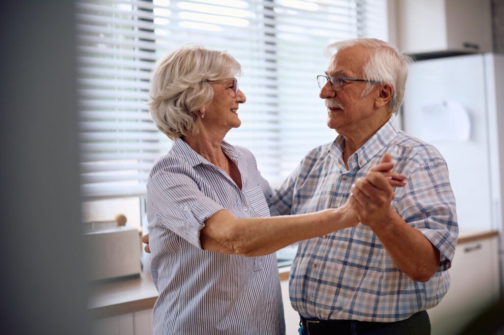 Happy retired couple dancing in the kitchen.